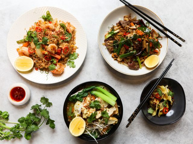 Four asian dishes nicely plated on a grey concrete background.