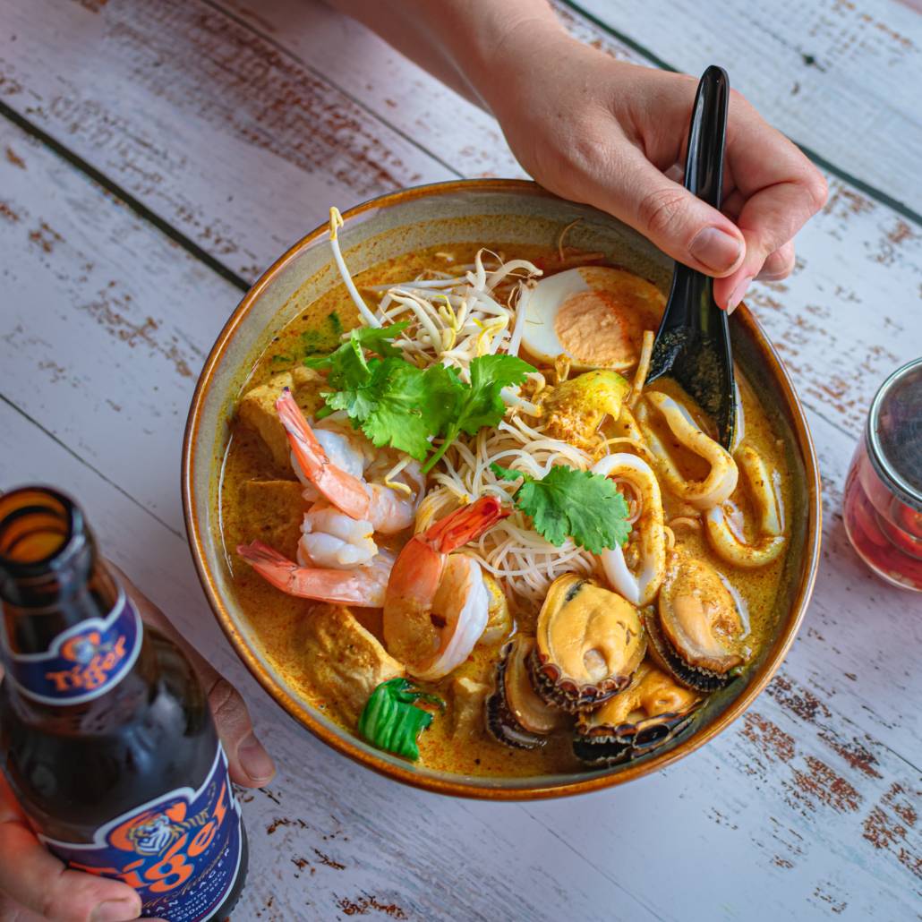 Bowl of laksa on a wooden table.